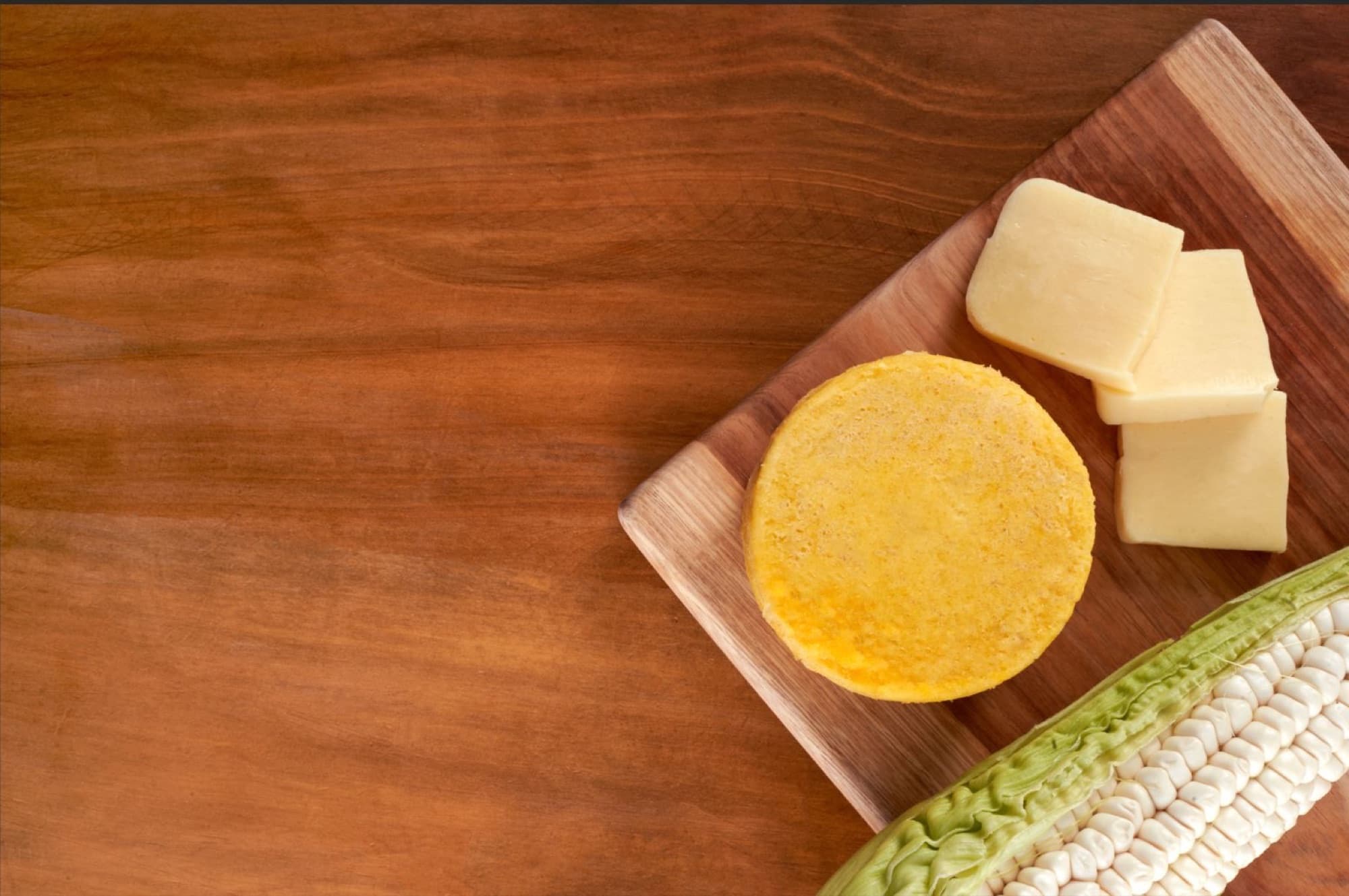 Top view of pastel de choclo on a board with cheese and corn