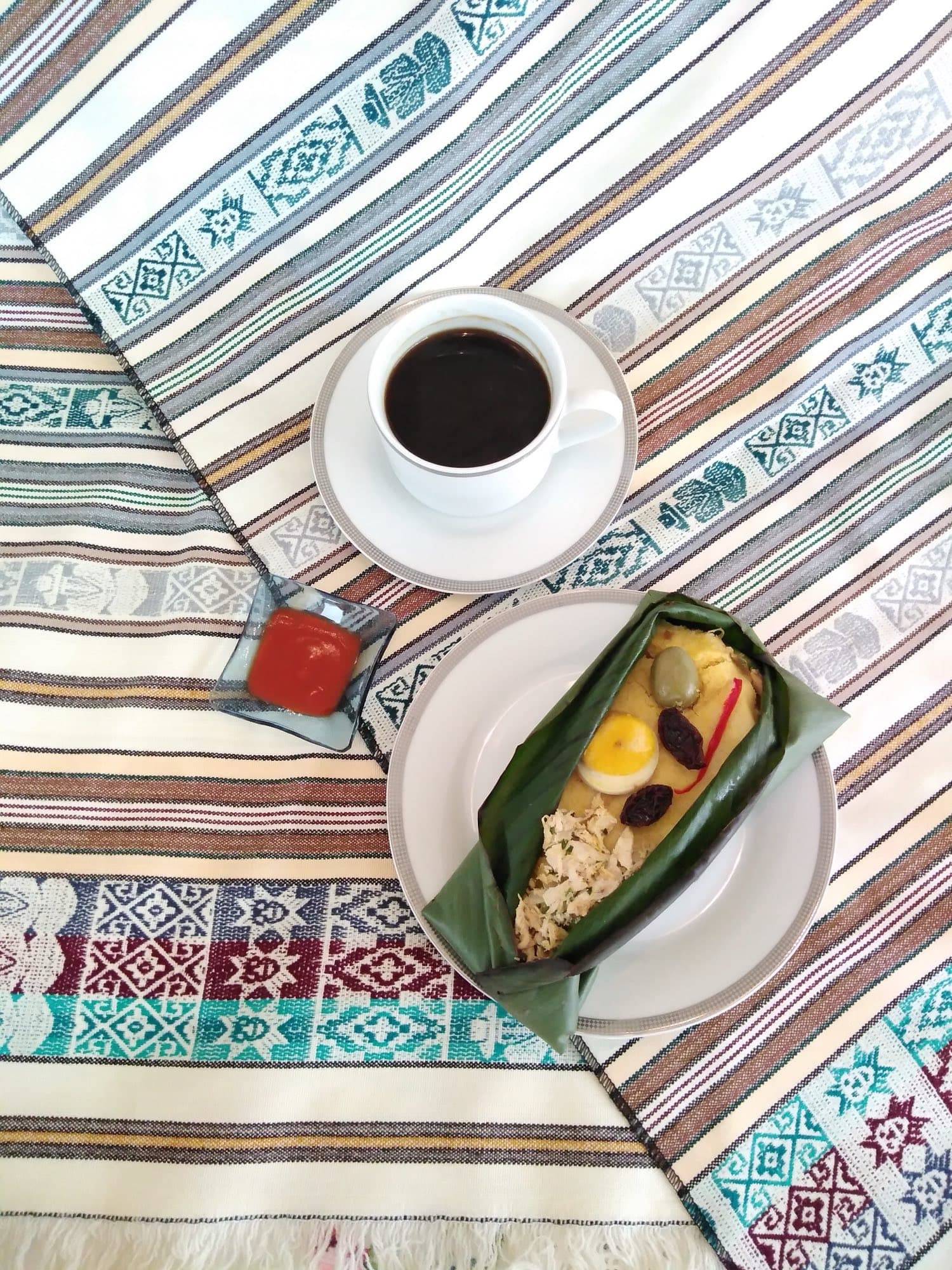 Tamal de pollo Kamimo con café sobre un mantel andino